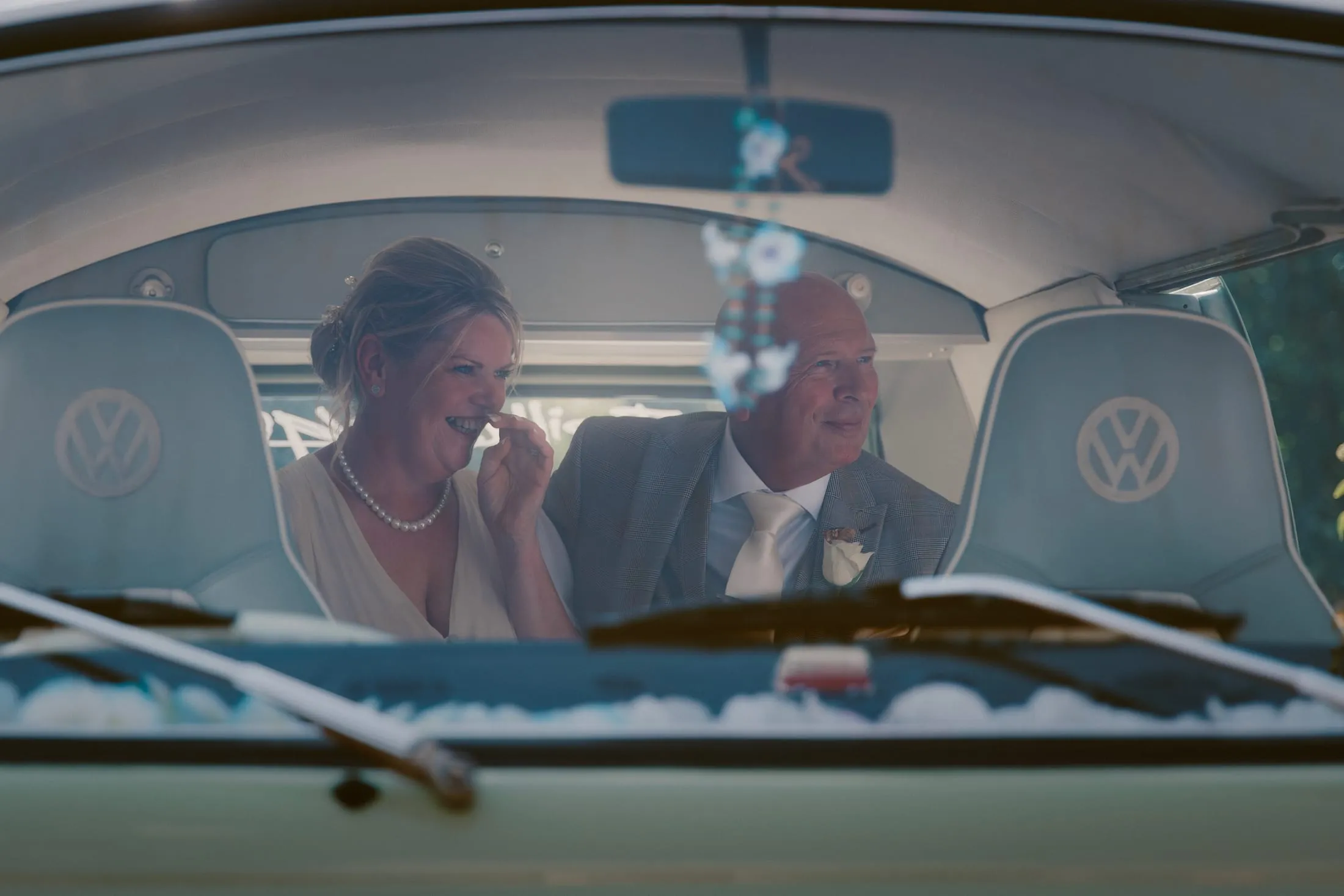 Bride and groom laughing together inside a vintage VW camper van