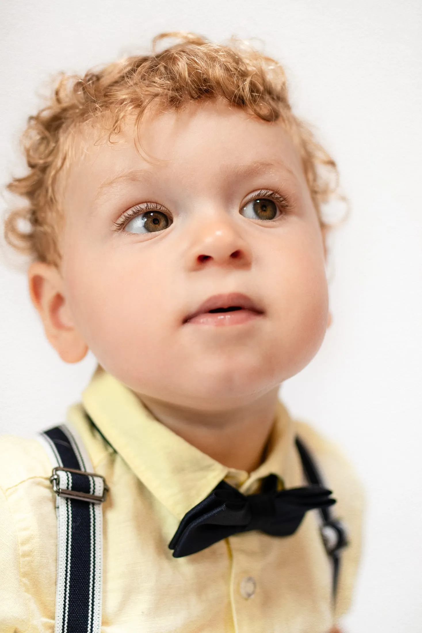 Curly-haired toddler in a yellow shirt and bow tie